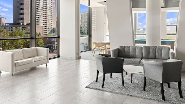 A spacious living area with a white sofa, grey armchairs, and a grey sectional sofa. - Oceana Suites Irarrazaval (Santiago)
