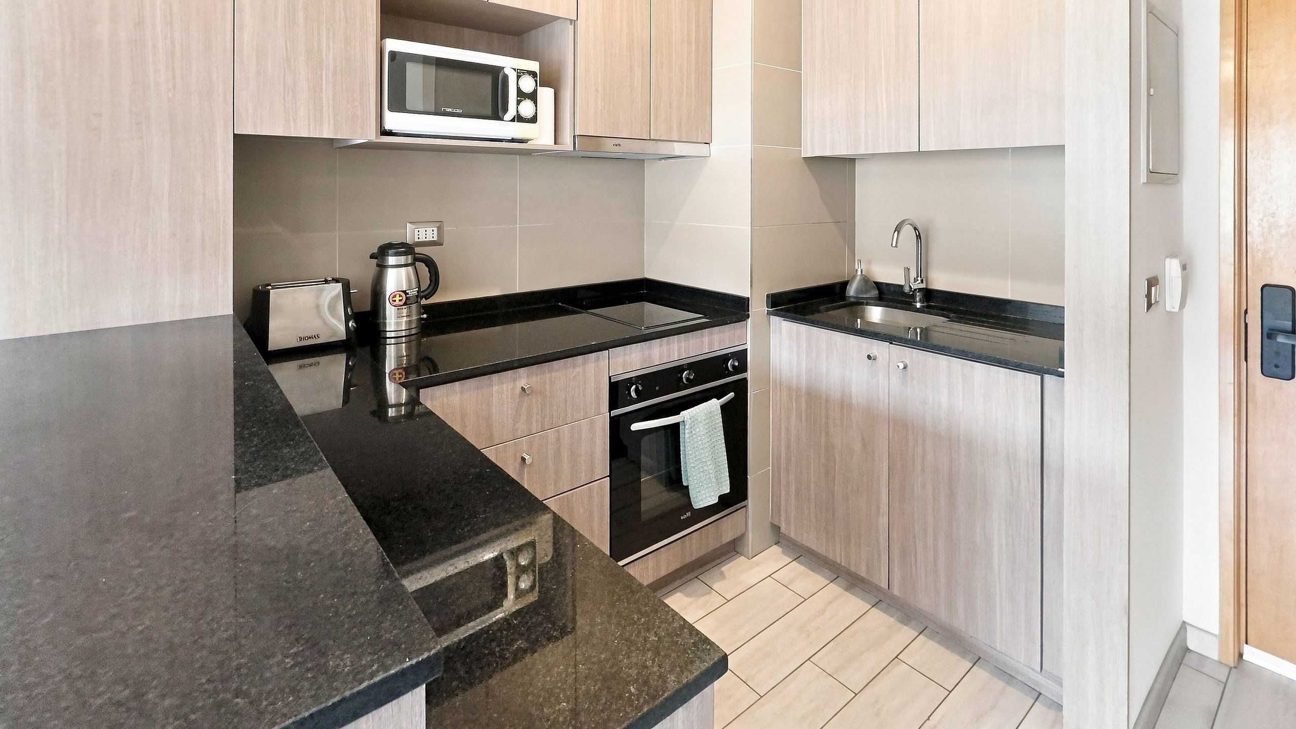 A modern kitchen with a microwave, toaster, kettle, and a sink.