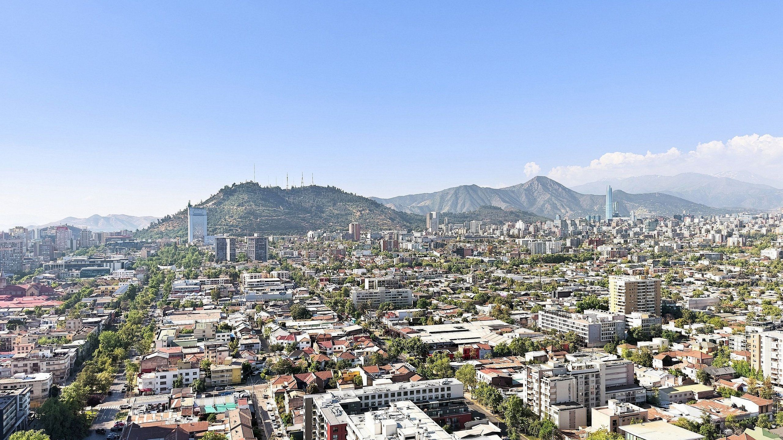 A cityscape with a prominent hill, buildings, and a clear sky.