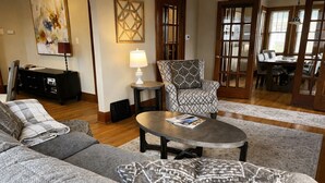 A living room with a sofa, armchair, coffee table, and a dining area with a table and chairs.
