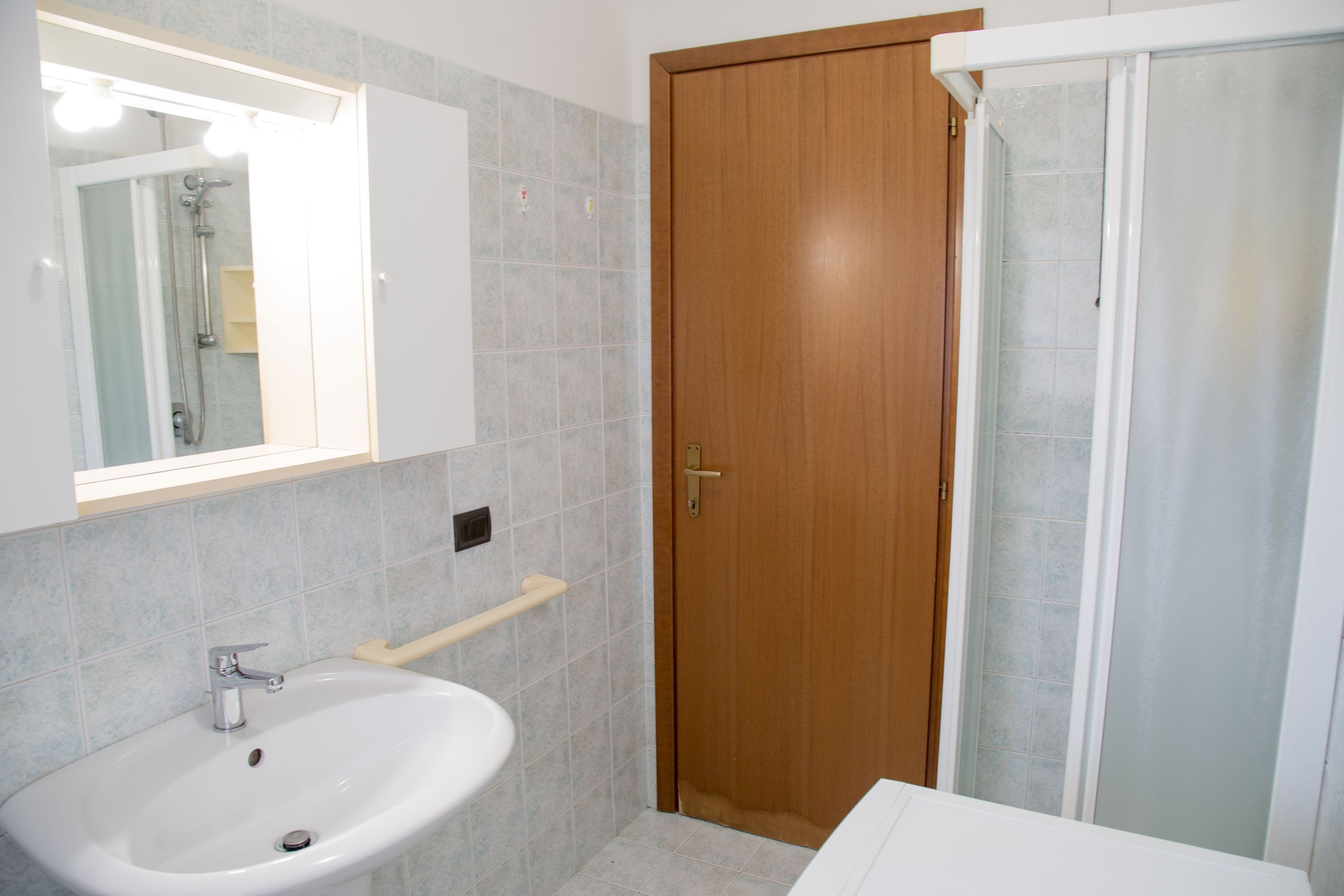A bathroom with a sink, mirror, and shower.