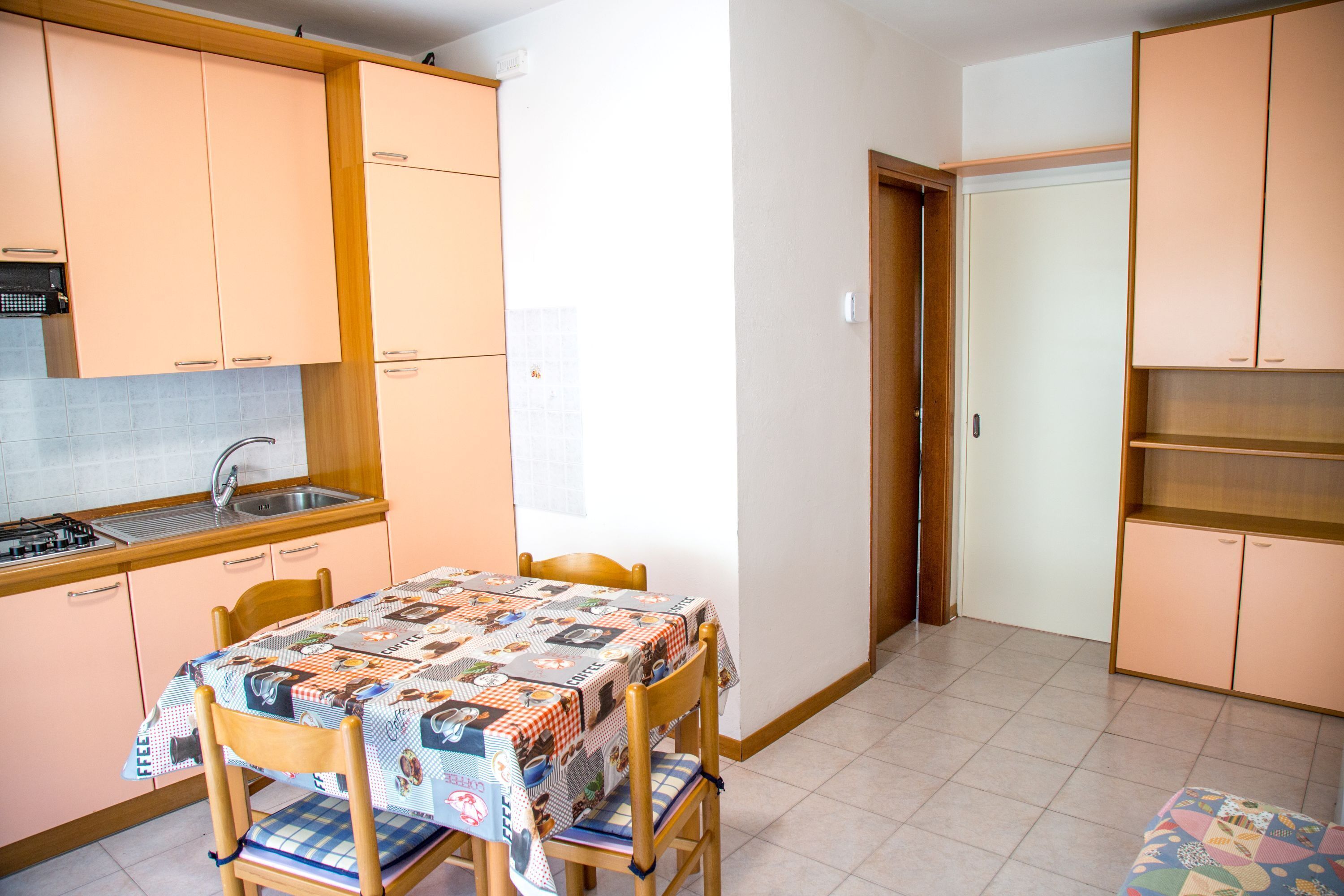 Una cocina funcional con mesa, sillas y un lavamanos pequeño.
