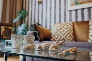 A living room with a glass coffee table, a sofa with patterned cushions, and a decorative alligator figurine. - 2 room apartment in Hamburg for 6 people (Hamburg)