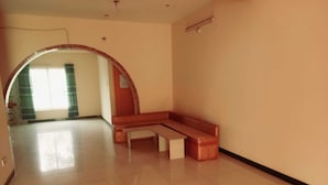 A spacious room with a bench and a tiled floor, an arched doorway, and a visible window with curtains. - Unique Village  (Ishurdi)