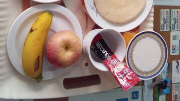 A tray with food items including bread, tomato sauce, a banana, an apple, and a Nescafe cup.