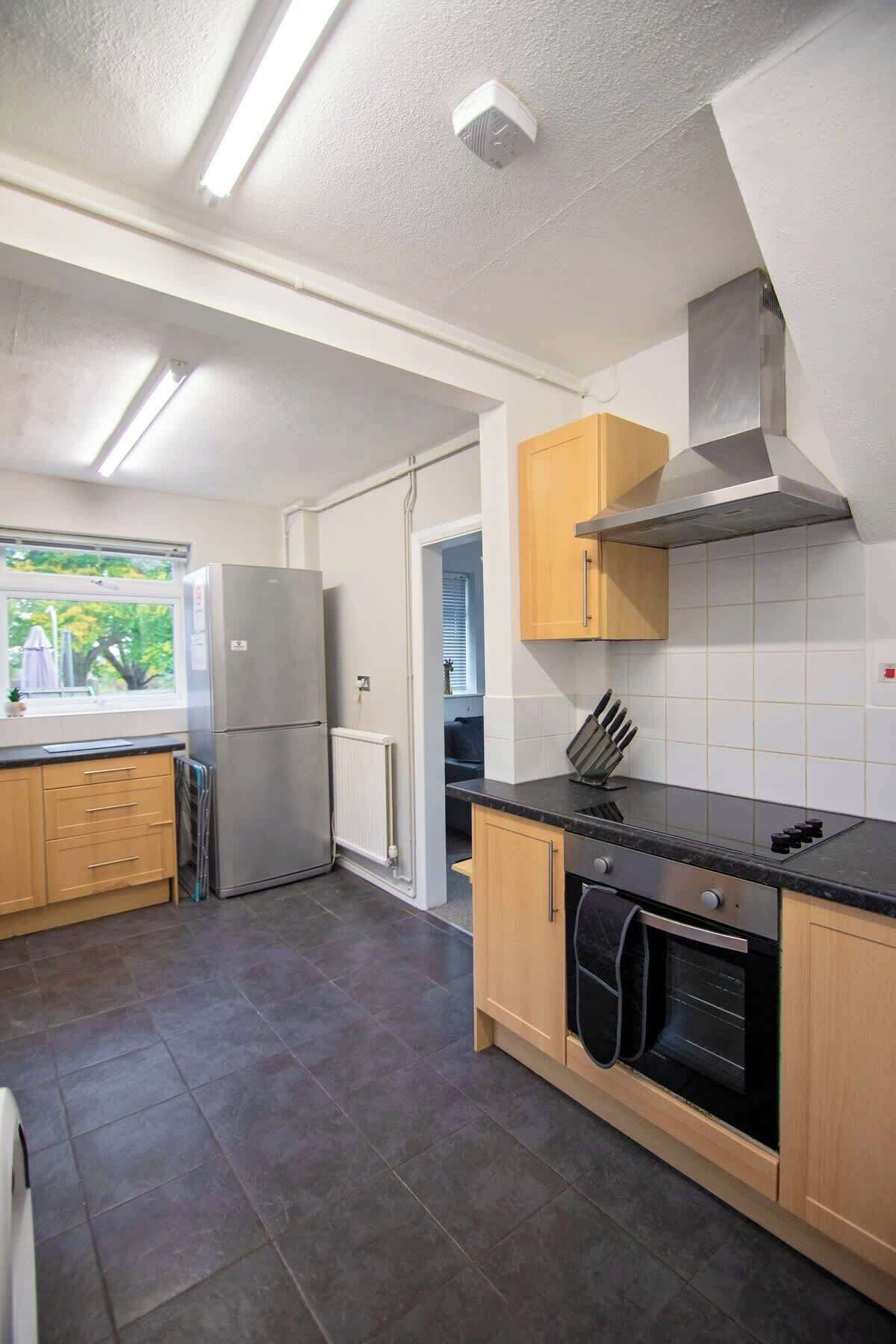 A modern kitchen with a built-in oven, a stainless steel range, and a window with a view of greenery.