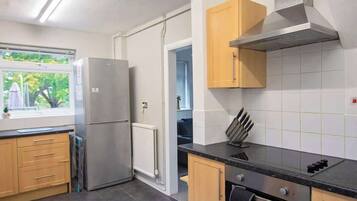 A modern kitchen with a built-in oven, a stainless steel range, and a window with a view of greenery.
