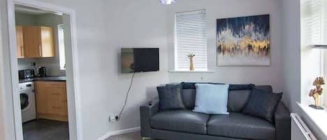 Una sala de estar con sofá, mesa de centro, televisor y un cuadro en la pared.