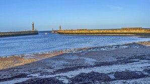 A coastal scene with a lighthouse, a breakwater, and a sandy beach. - No.3 Sandside (Whitby)