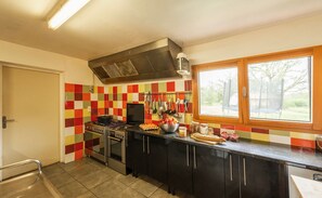 A kitchen with a gas stove, oven, and a window with a view of trees. - Unforgettable Reunions in the Countryside – Sleeps 28 to 32 Guests (Lalbenque)