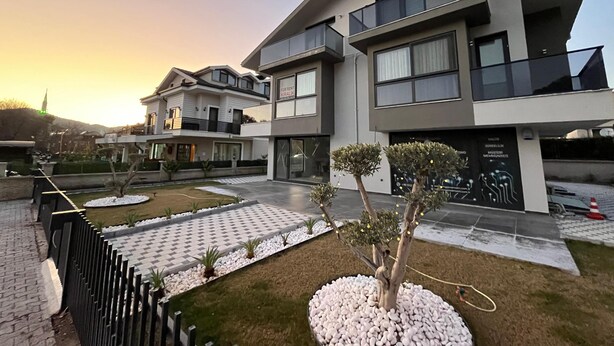 Une maison moderne à deux étages, dotée d’une allée pavée et d’un petit jardin.