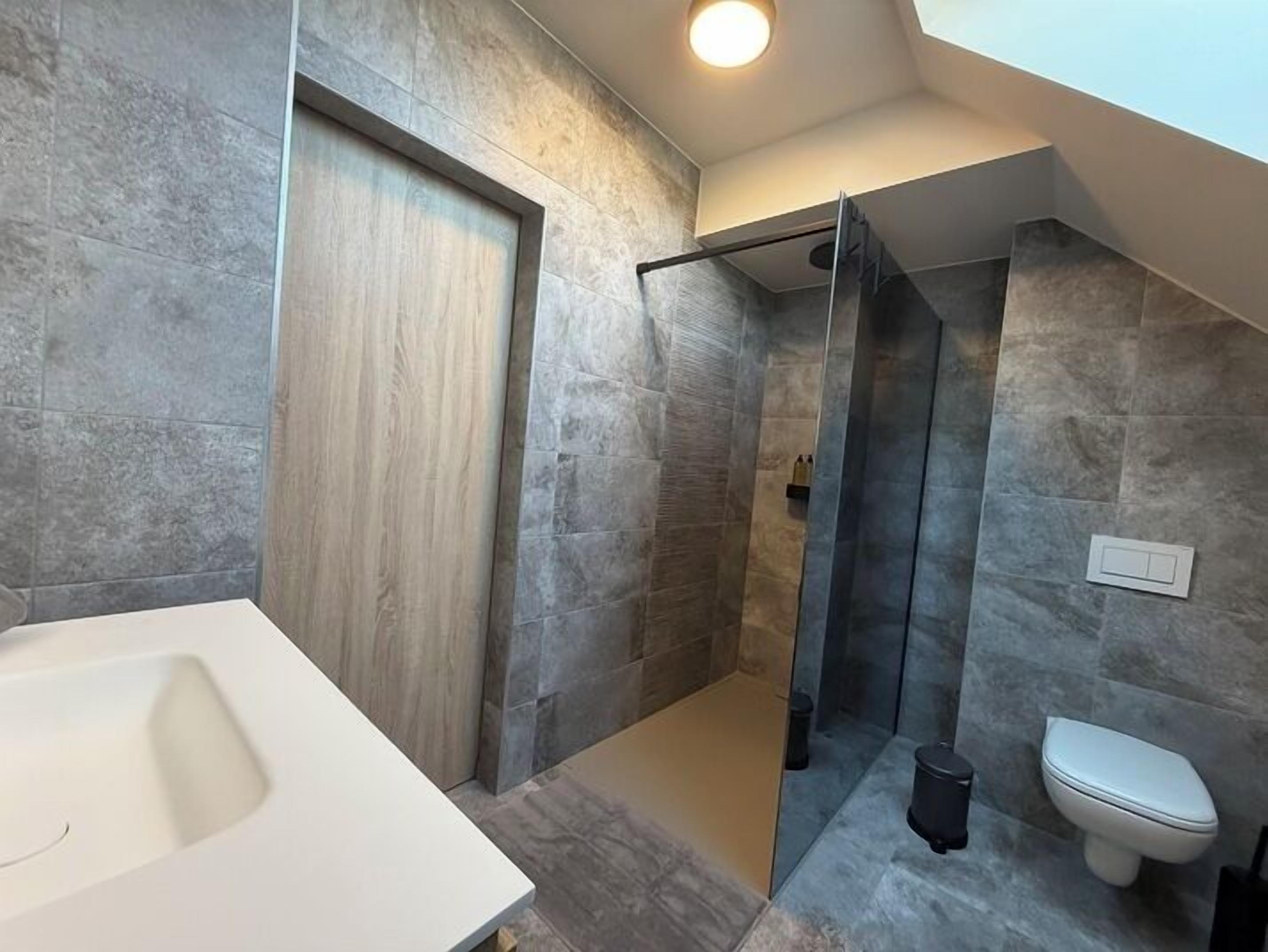 A modern bathroom with a shower, toilet, and sink.