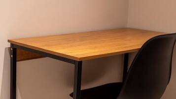 A corner desk with a black chair, wooden legs, and a black metal frame.