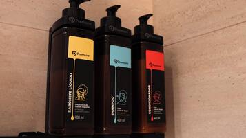 Three black Premier toiletries dispensers on a beige wall.