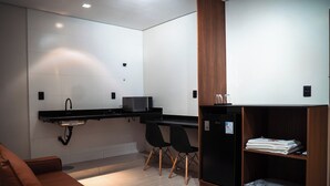 Een moderne keuken met een magnetron, zwarte stoelen, een houten kast en een bruine bank.