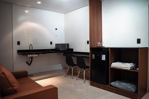 Una cocina moderna con microondas, sillas negras, un mueble de madera y un sofá marrón.