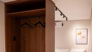 Een compacte slaapkamer met een bed, een kast met planken en een kleine koelkast.