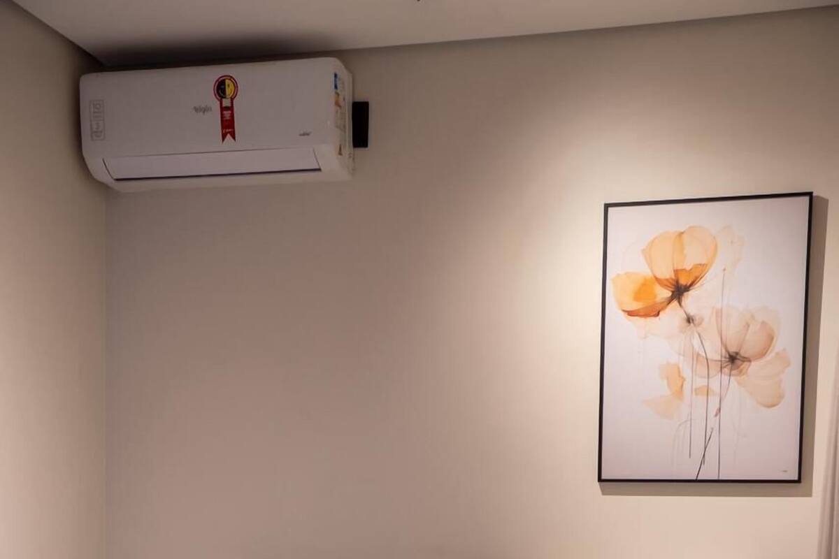 Una habitación de hotel con una cama, ropa de cama blanca, una obra de arte floral enmarcada en la pared y una bandeja con vasos sobre la cama.