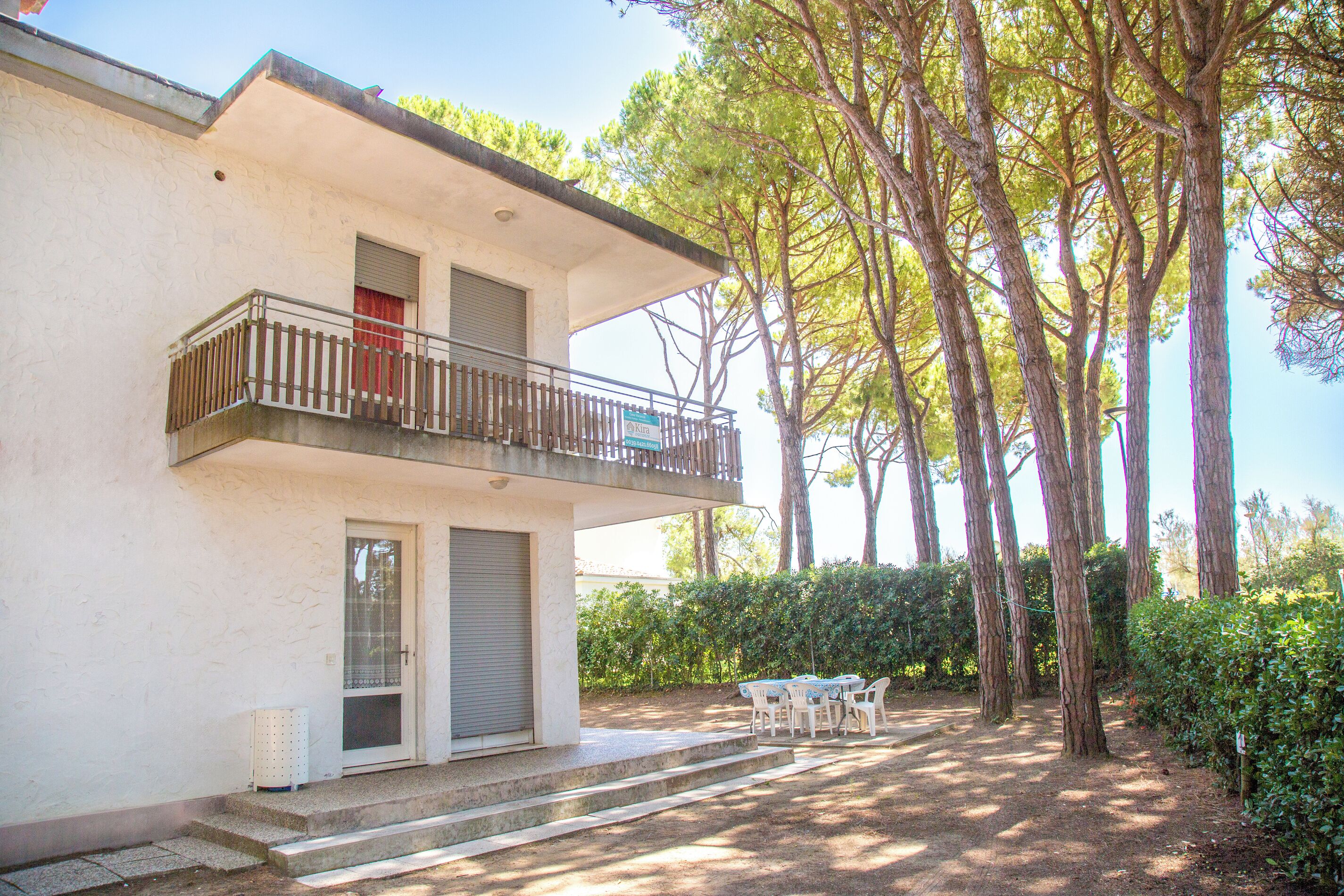 A two-story building with a balcony, a door, and a small outdoor seating area with a table and chairs.