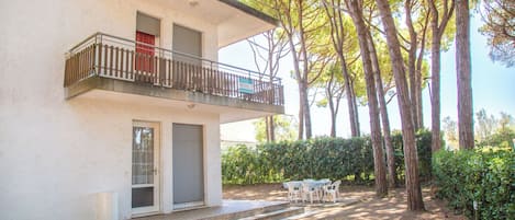 A two-story building with a balcony, a door, and a small outdoor seating area with a table and chairs.
