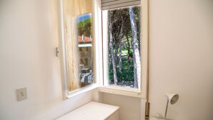 Una habitación pequeña y limpia con ventana, escritorio y una silla.