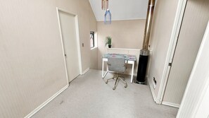 Una habitación pequeña y luminosa con escritorio, silla y una planta en maceta.