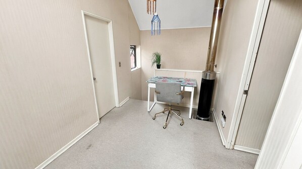 A small, well-lit room with a desk, chair, and a potted plant.
