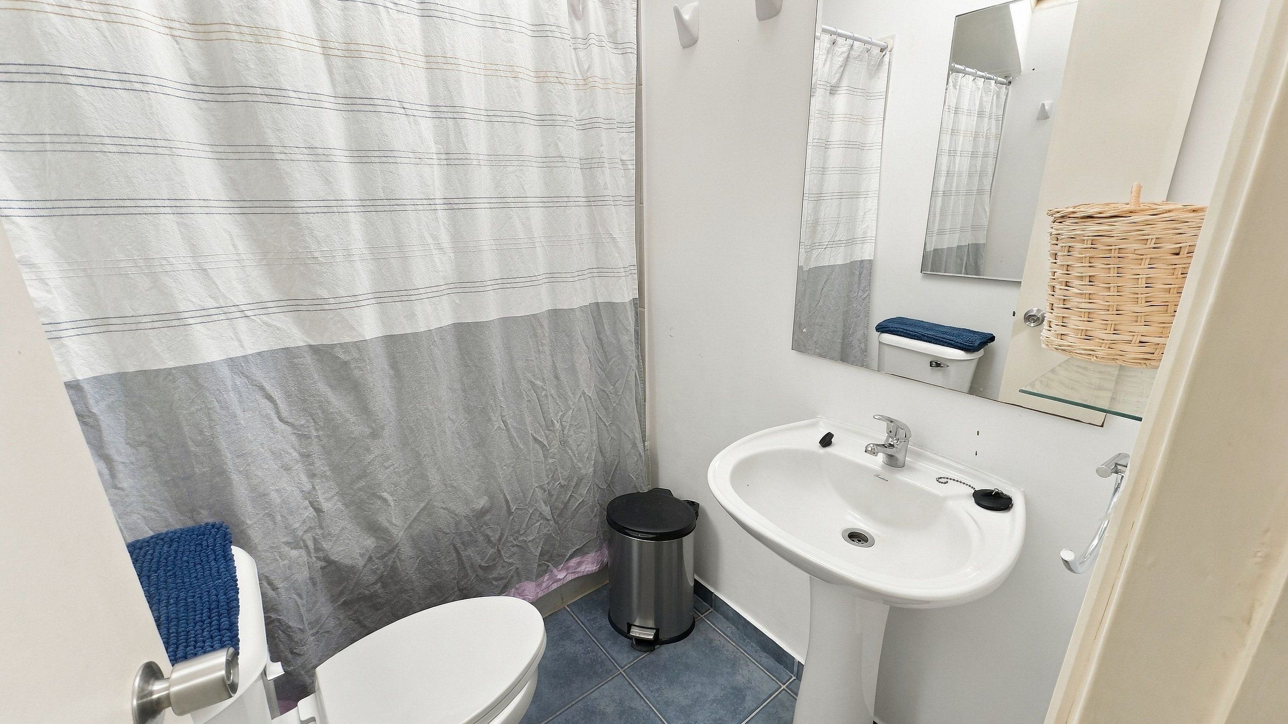 A small bathroom with a toilet, sink, and shower curtain.