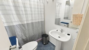 Un baño pequeño con inodoro, lavabo y cortina de ducha.
