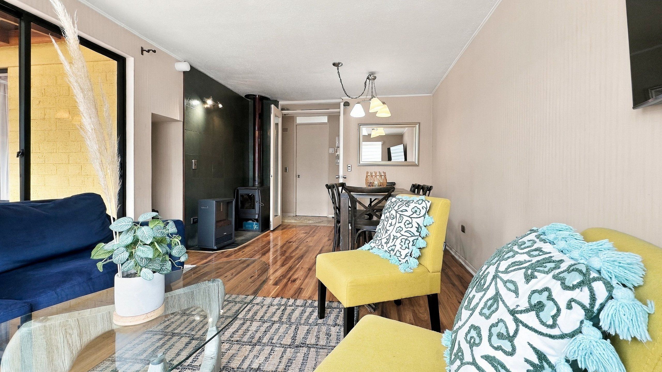 Een woonkamer met een bank, fauteuil en een bijzettafeltje met een plant.