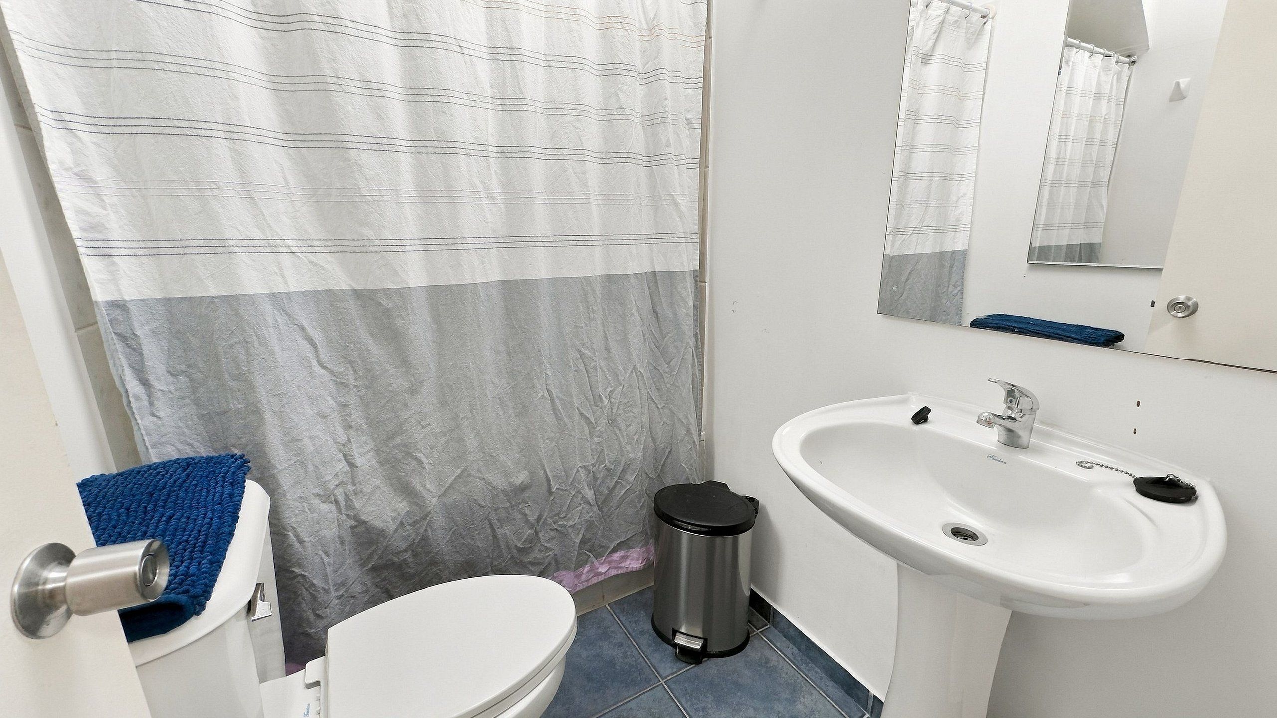 A bathroom with a toilet, sink, and shower curtain.