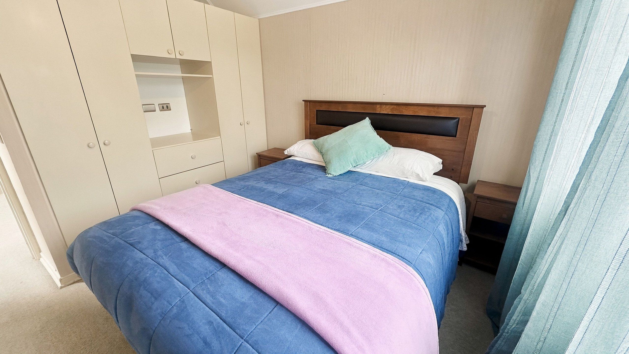 Une chambre à coucher avec un lit, une armoire et une table de chevet.