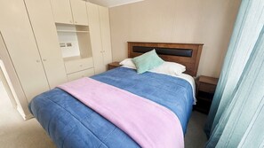 A bedroom with a bed, a wardrobe, and a nightstand.