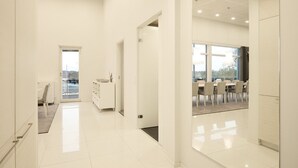 Un hall d’entrée moderne et spacieux, avec un coin repas visible à travers une porte vitrée.