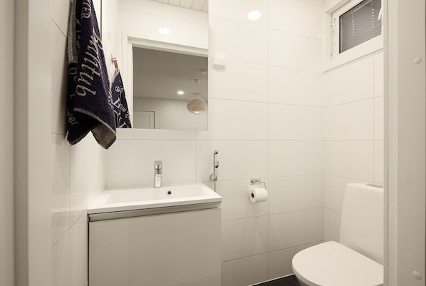 A bathroom with a white sink, mirror, and toilet.