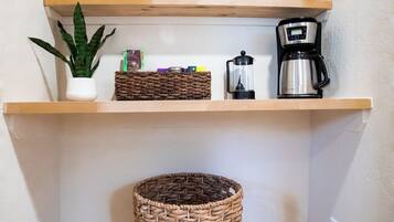 Une cuisine avec des étagères en bois où sont rangés divers ustensiles de cuisine, une machine à café et une plante en pot.