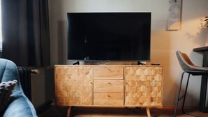 Un salon moderne avec un meuble en bois, un téléviseur à écran plat et un fauteuil.