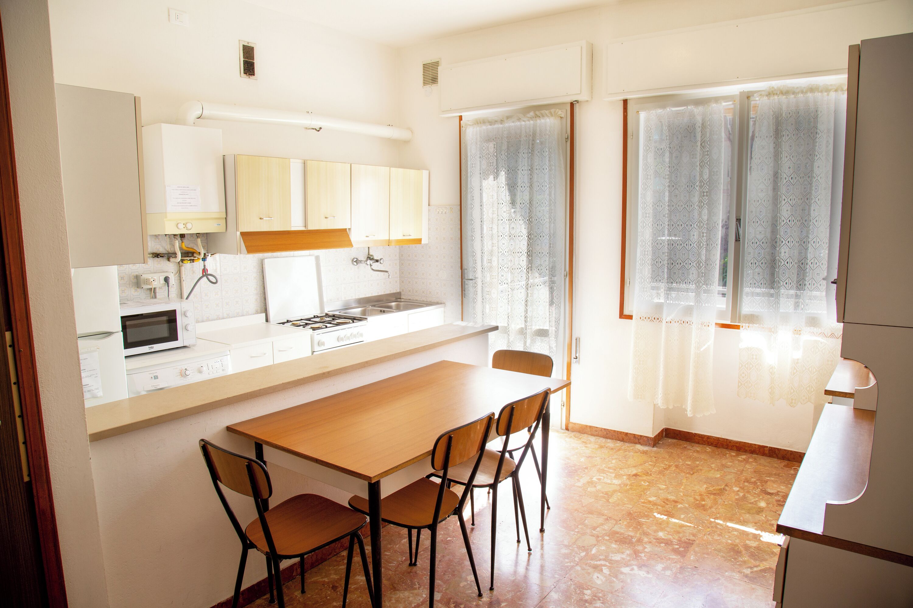 Uma cozinha compacta com mesa, cadeiras, micro-ondas, fogão e armários.