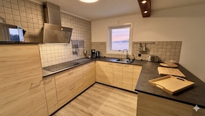 A modern kitchen with wooden cabinets, a black countertop, a window with a view, and a built-in oven.