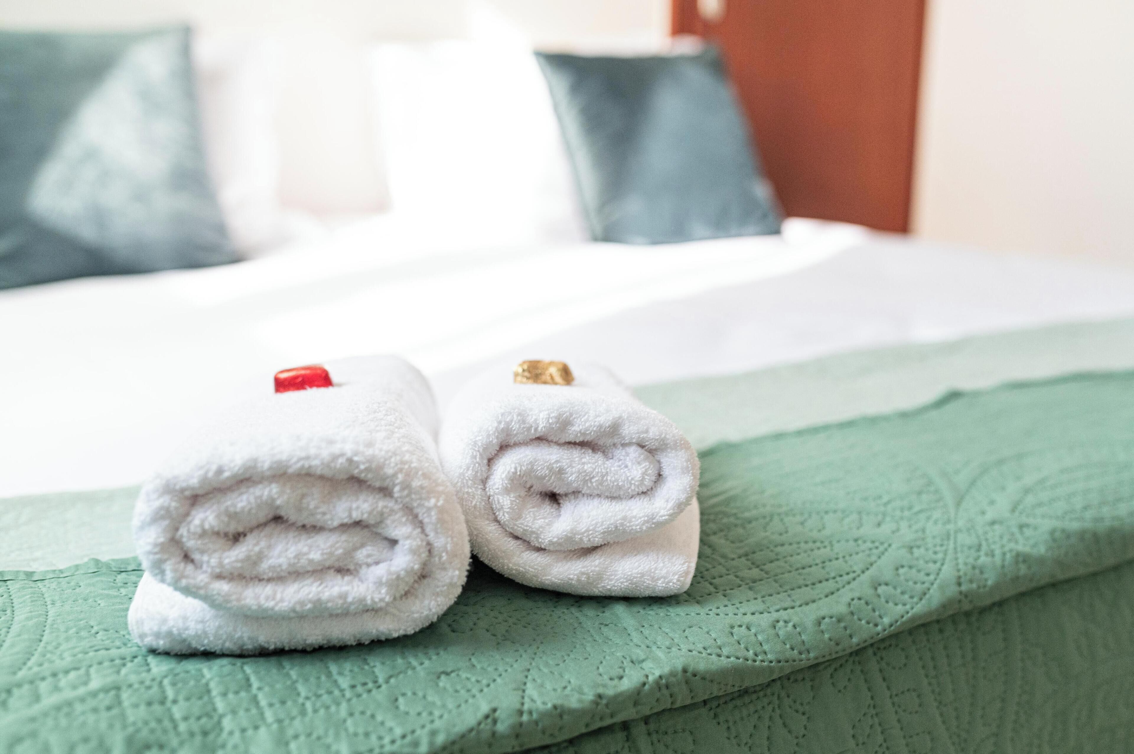A neatly made bed with white linens and a green quilted blanket.