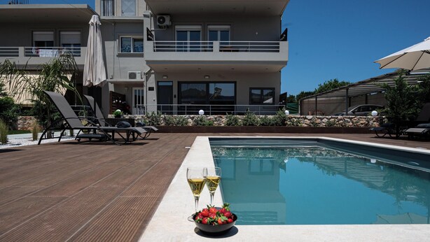 A modern pool area with lounge chairs, a pool table, and a bowl of strawberries and lemons. - Lumina Apartment with Shared Pool (Perivolia)
