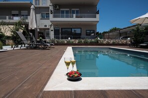 A modern pool area with lounge chairs, a pool table, and a bowl of strawberries and lemons. - Lumina Apartment with Shared Pool (Perivolia)