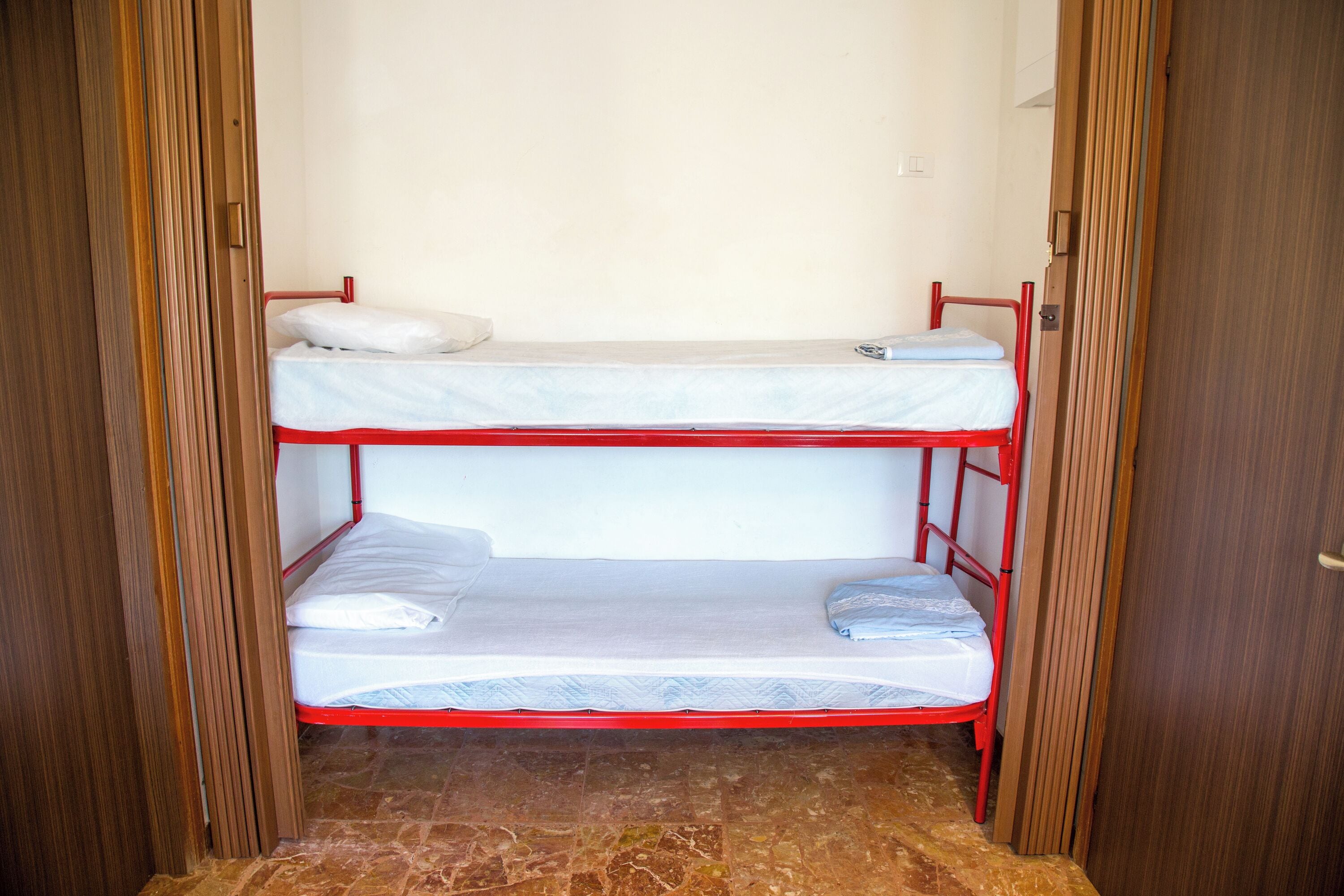 Quarto com beliche, moldura de porta de madeira e chão de azulejos.