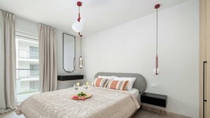 Un dormitorio moderno con una cama grande, una mesita de noche, un espejo y una ventana con cortinas.
