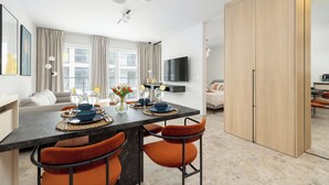 Una sala de estar moderna con comedor, un sofá, un televisor montado en la pared y un amplio armario de madera.