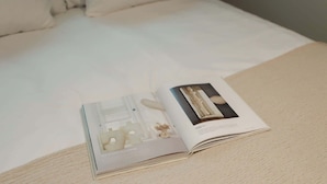 A magazine on a bed with a white cover. - Dam Residence's Classic Suite (Zaandam)