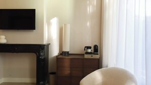 A hotel room with a flat-screen TV mounted on the wall, a small table with a coffee maker, a candle, and a marble base. - Dam Residence's Classic Suite (Zaandam)