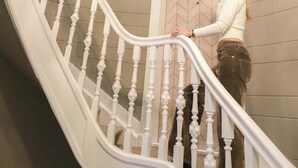 A staircase with white balusters and a handrail, leading to a door with a geometric pattern. - Dam Residence's Classic Suite (Zaandam)