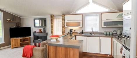 A compact kitchen with a central island, a built-in microwave, and a stove.
