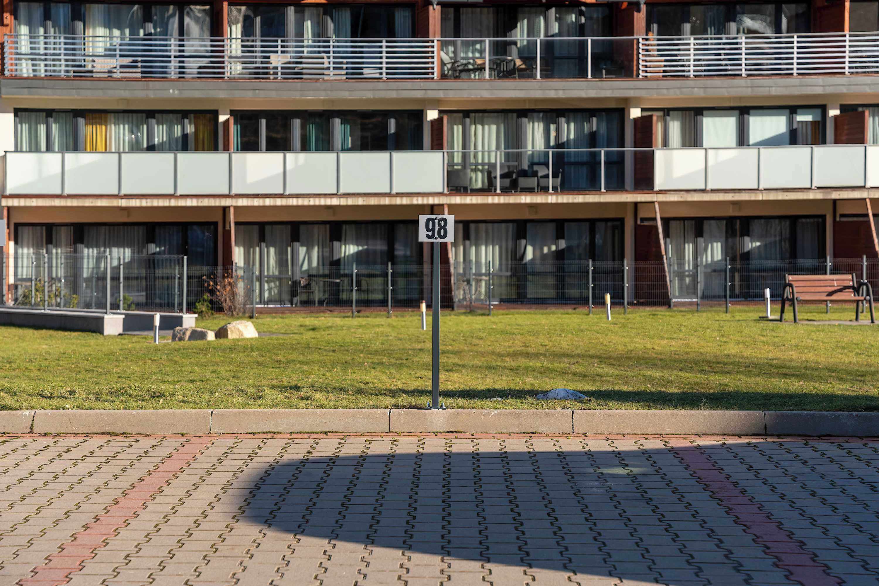 Um edifício com vários andares, teto plano, amplas janelas e uma área gramada na frente.